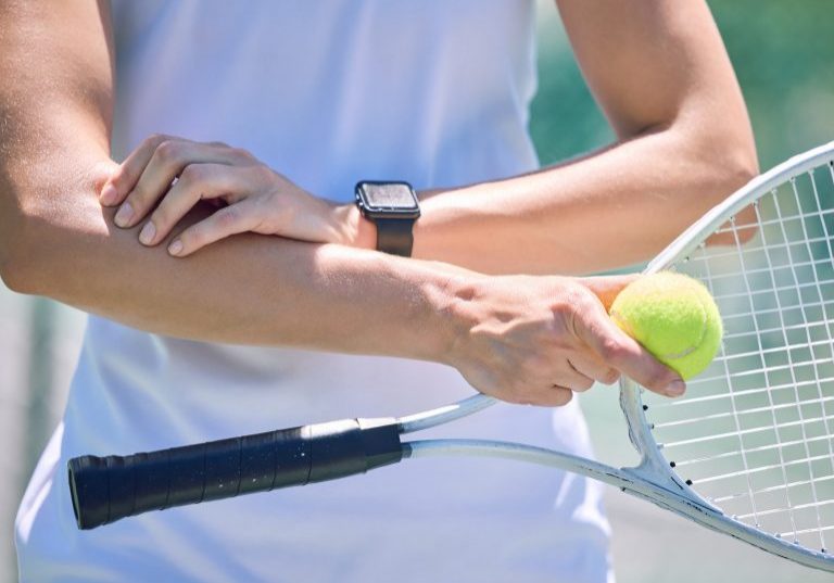 Sports, arm pain and tennis player with a racket and ball standing on a court during for a match. Closeup of a health, strong and professional athlete with equipment touching a medical elbow injury