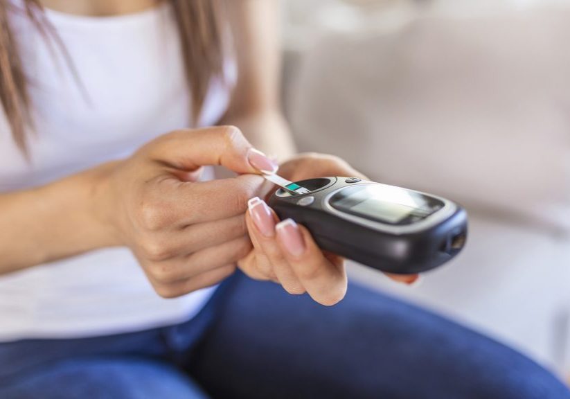 Woman with glucometer checking blood sugar level at home. Diabetes, health care concept. Young woman using digital glucometer at home. Diabetes control