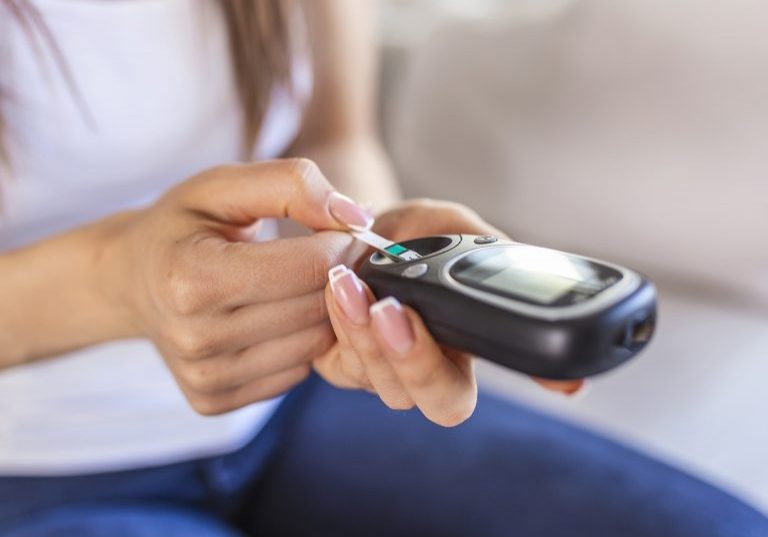 Woman with glucometer checking blood sugar level at home. Diabetes, health care concept. Young woman using digital glucometer at home. Diabetes control