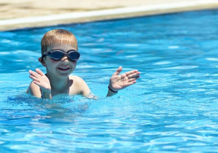Kid swimming in the pool. Summertime holidays